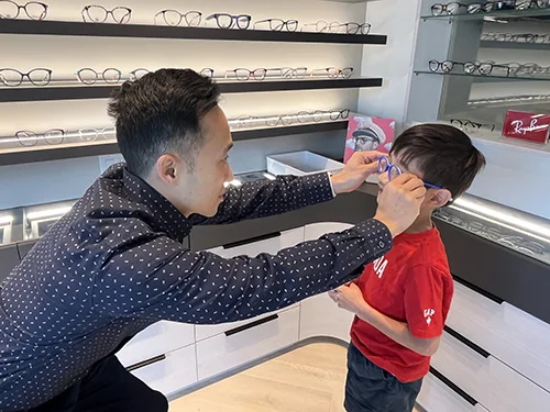 Dr. Yu fitting a child with glasses